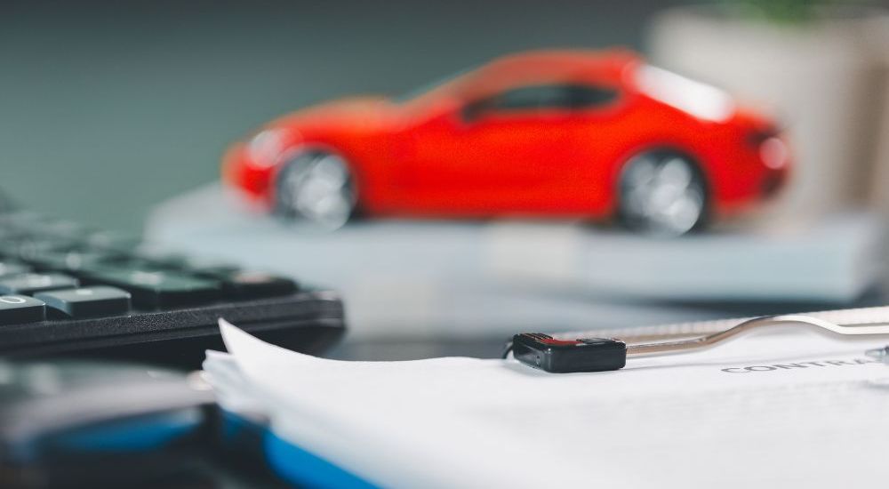 Calculator, car model, and contract papers on a desk, symbolizing auto finance and leasing agreements.