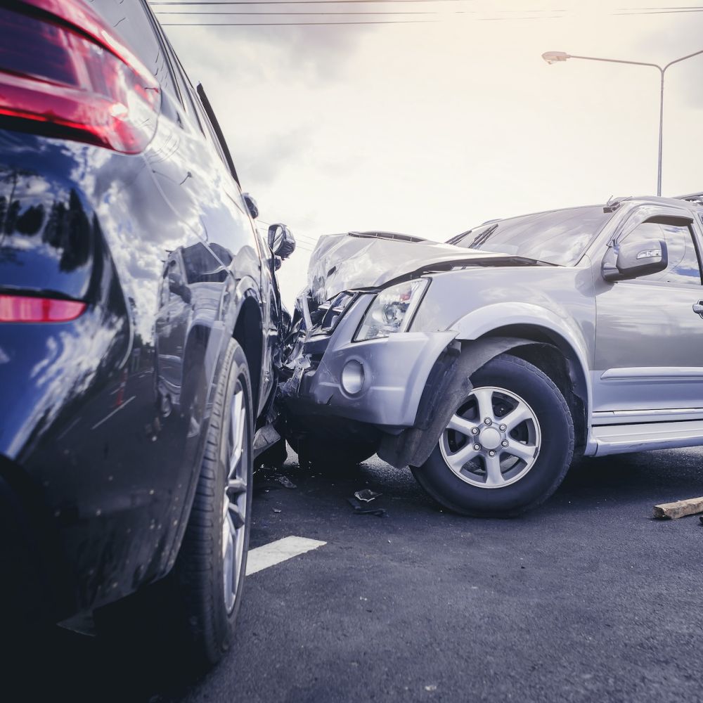 Two SUVs in a severe road collision on a cloudy day, showcasing vehicle damage and accident scene.