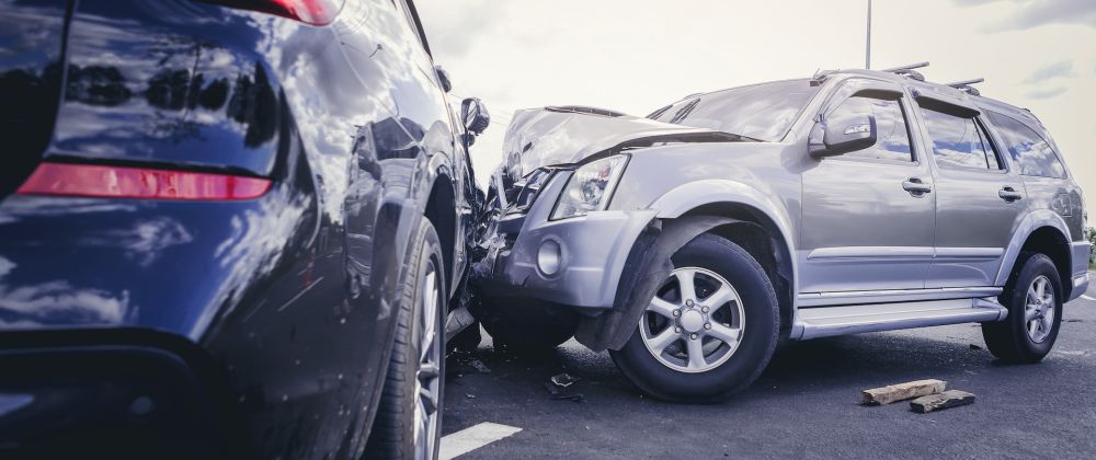 Two SUVs in a severe road collision on a cloudy day, showcasing vehicle damage and accident scene.