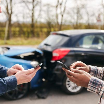 two men standing next to each other looking at their cell phones