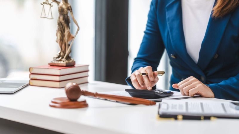 a woman sitting at a desk in front of a statue of a lady justice