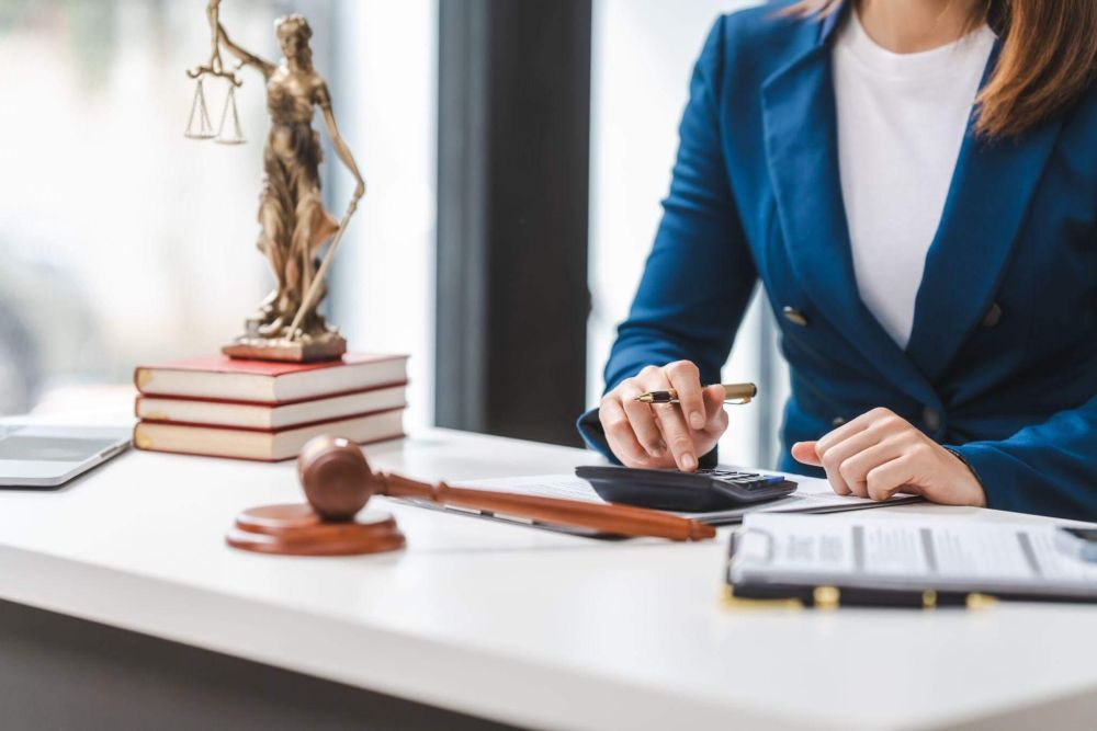 a woman sitting at a desk in front of a statue of a lady justice