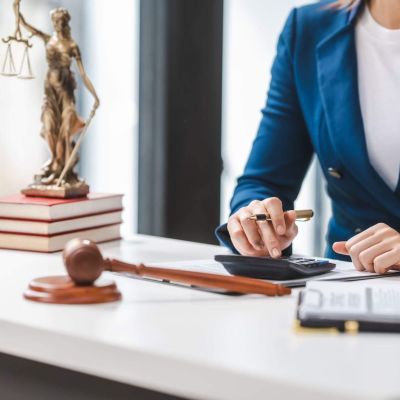 a woman sitting at a desk in front of a statue of a lady justice