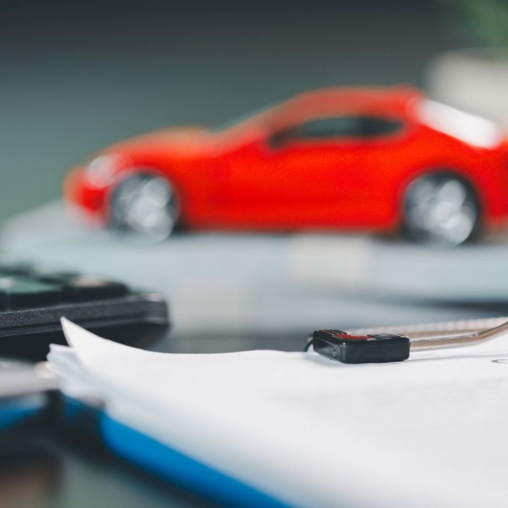 Calculator, car model, and contract papers on a desk, symbolizing auto finance and leasing agreements.