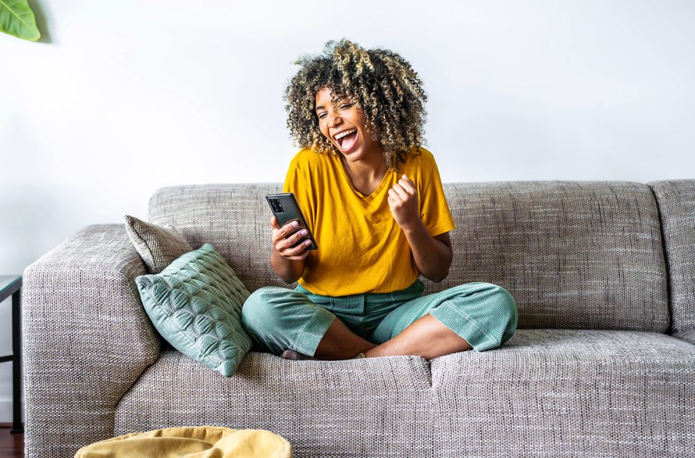 Excited happy young black woman holding smart phone device