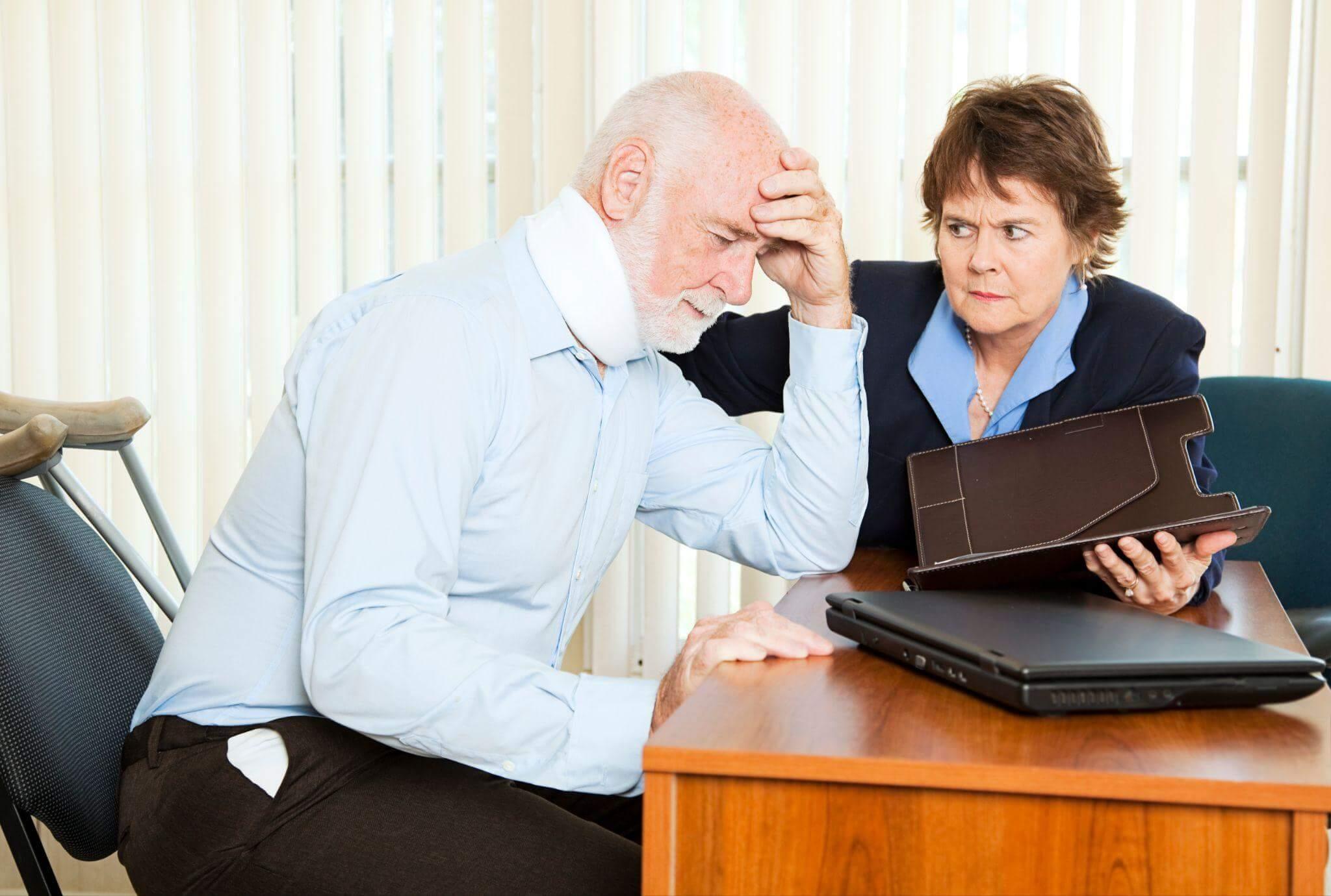 a man and woman sitting at a table with a laptop, the man seems worried about something he is reading in a document