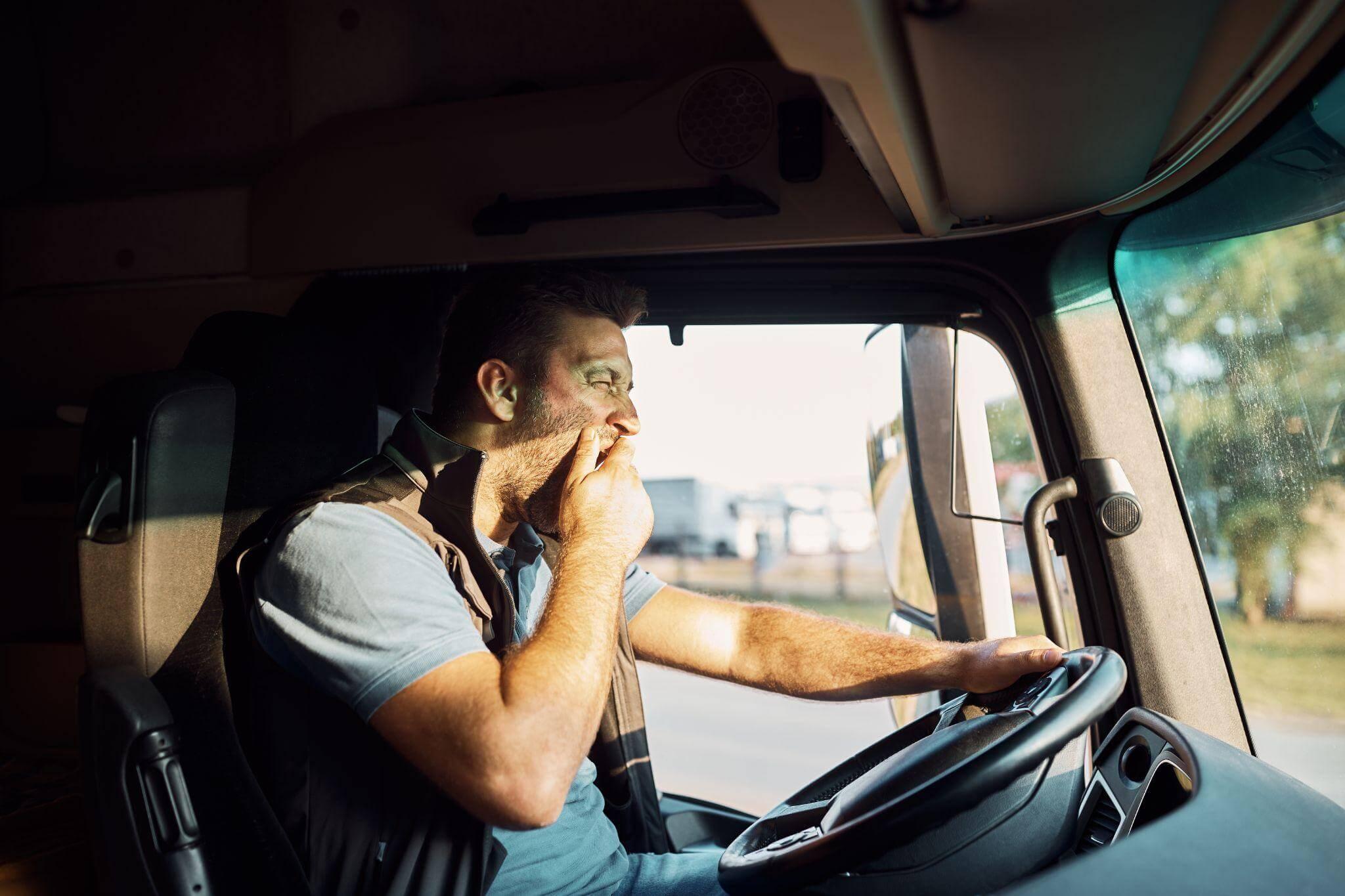 a man driving a truck, he is yawning and seems to be tired