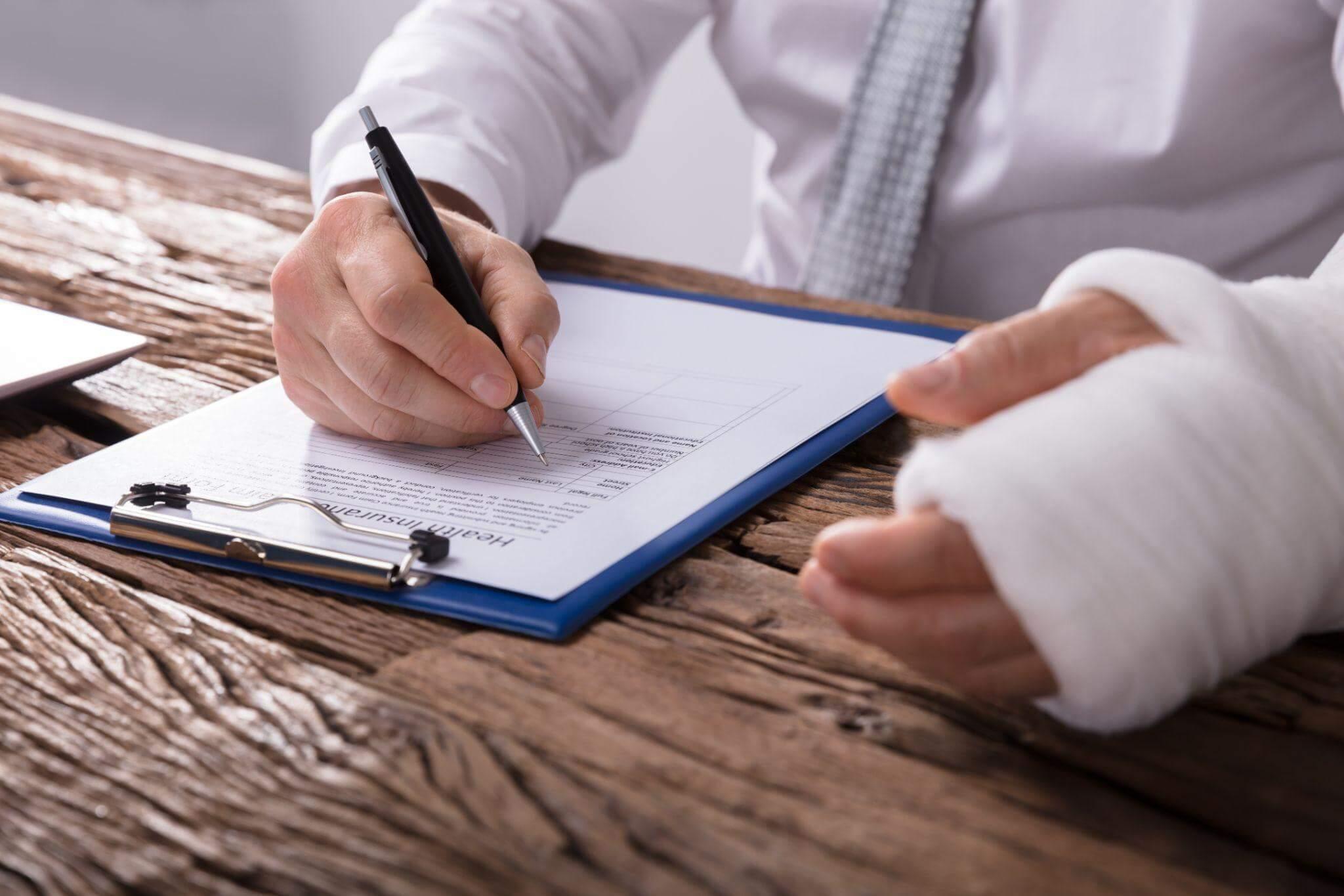 a person with a cast on their arm writing on a piece of paper