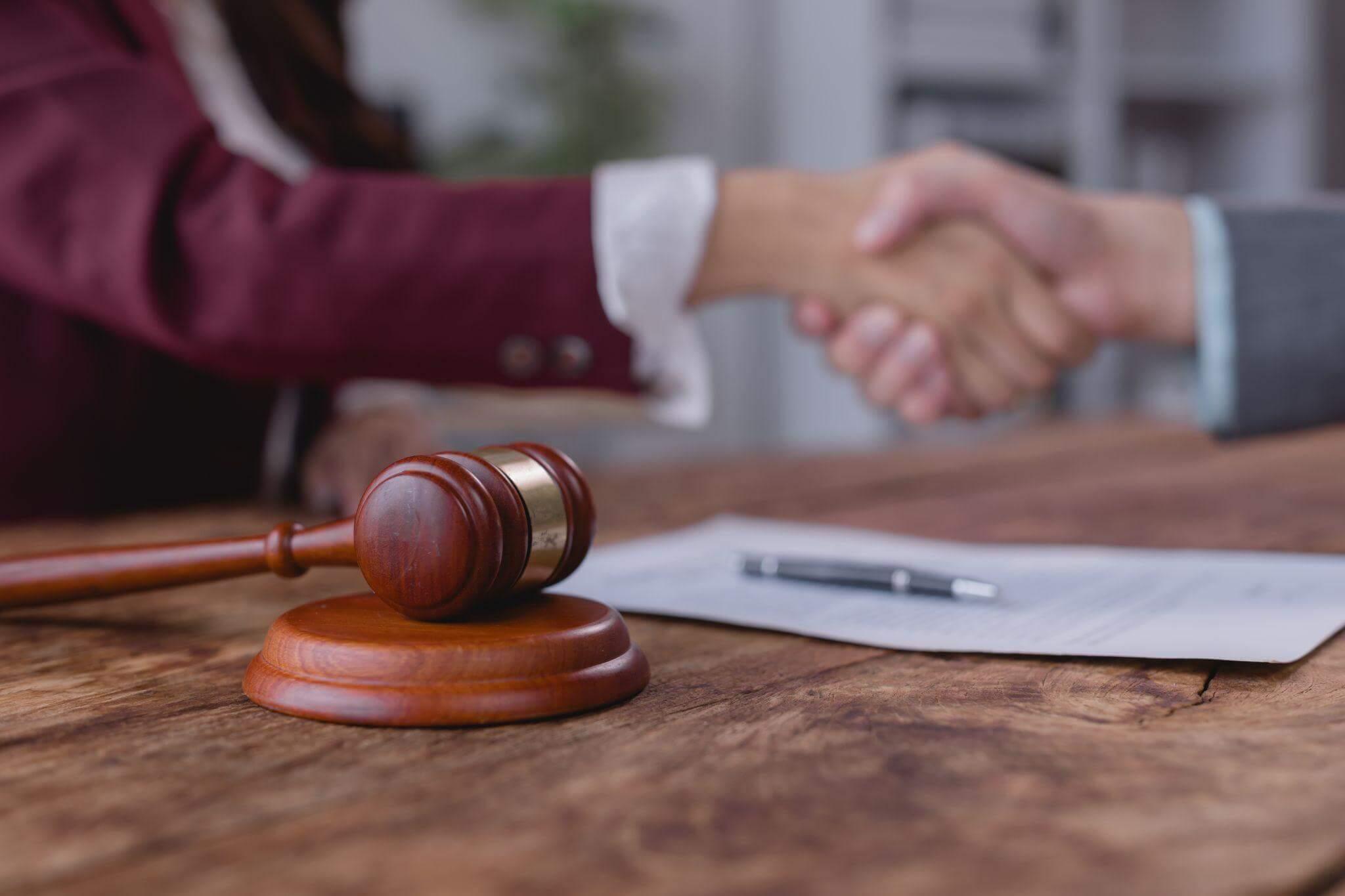 two people shaking hands over a wooden table after signing a document